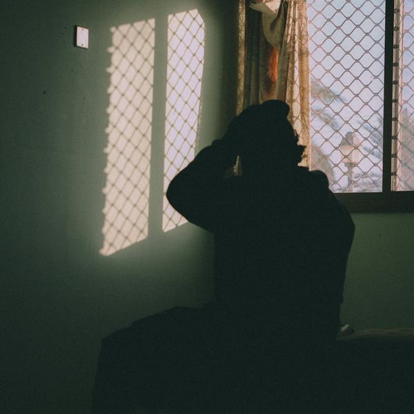 Person meditating in a calm, dark room with cyan light.